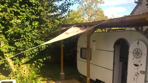 Un camping-car blanc avec une boussole sur le côté, une terrasse en bois et un espace patio couvert.