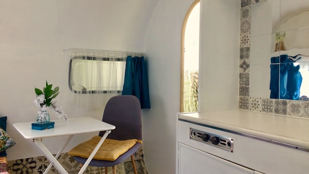 Une petite cuisine équipée comprenant une table, une chaise et une fenêtre avec des rideaux.