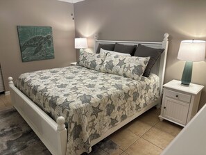 Ein Schlafzimmer mit einem Bett, Nachttischen, einer Lampe und einem Wandbild.