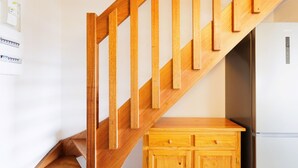 Eine Holztreppe mit einem Holzkasten und einem weißen Kühlschrank im Hintergrund.