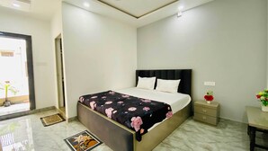 Een moderne slaapkamer met een bed, nachtkastje en een klein bureau met stoel.