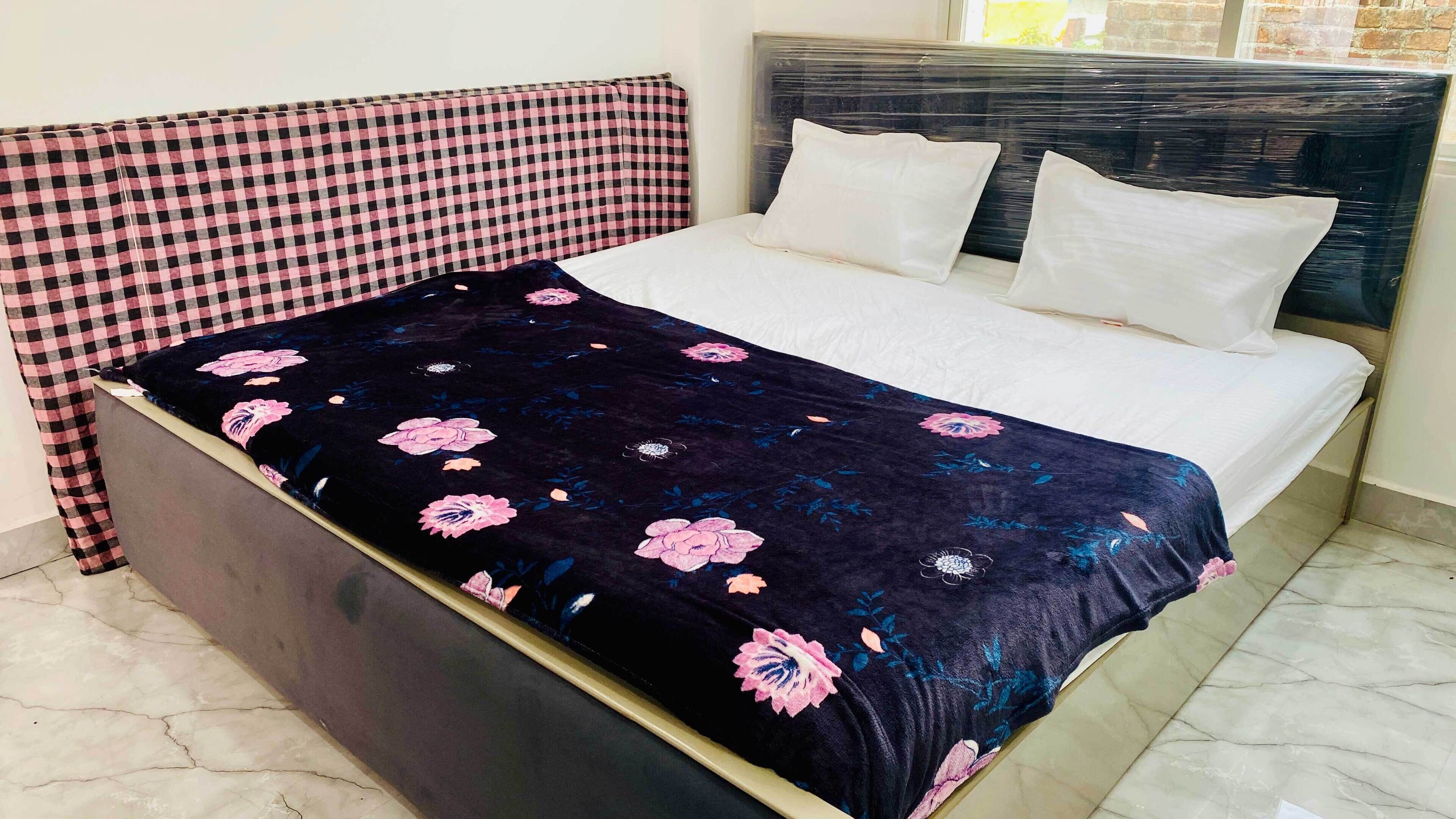 A bed with a floral bedspread, a checkered headboard, and white pillows.