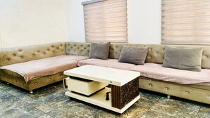 Een hoeksalon met een beige modulaire bank, een witte salontafel en een vloer van marmertegels.