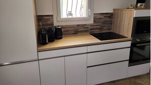 A modern kitchen with a built-in stove, a window with a view, and a wooden countertop. - Charming apartment (Allauch)