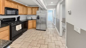 A modern kitchen with wooden cabinets, a stainless steel refrigerator, and a black stove.