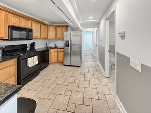 A modern kitchen with wooden cabinets, a stainless steel refrigerator, and a black stove. - Stylish Old City Flat: 3BD Fits 6 Near LibertyBell (Philadelphia)