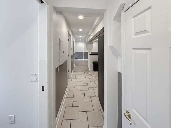 A hallway with white walls, a tiled floor, and a door with a brass handle.