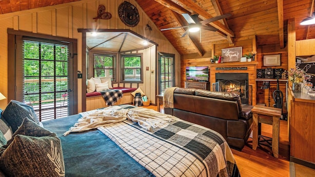 L’intérieur d’un chalet confortable, avec un grand lit, une cheminée, un canapé en cuir et un coin repas.