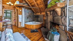 A cozy cabin interior with a stone fireplace, a wooden ceiling, and a stone wall. - Hot Tub! Cute Studio Cabin! Views! Private! Relax! (Sevierville)