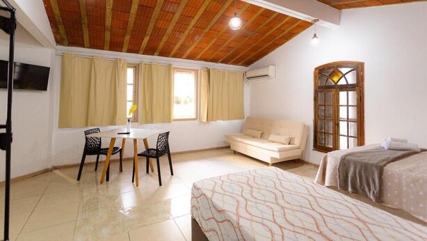 A room with a wooden ceiling, a bed, a sofa, a table with chairs, and a TV. - 360 Casa Praia Botafogo By SUHCasa (Rio de Janeiro)