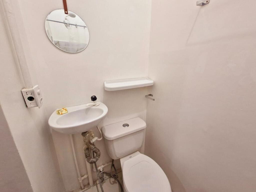Un baño pequeño y blanco con inodoro, lavamanos y espejo.