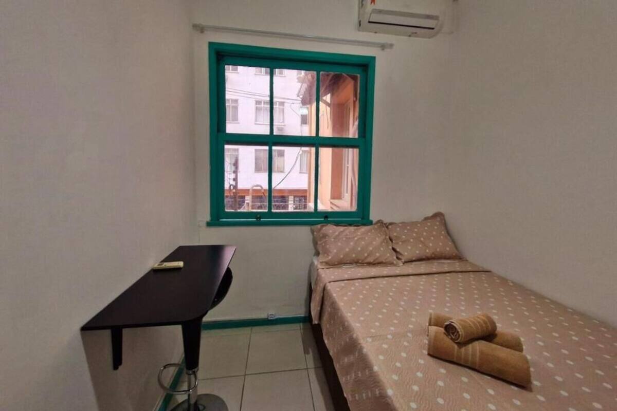Una habitación pequeña y sencilla con cama, escritorio y ventana.