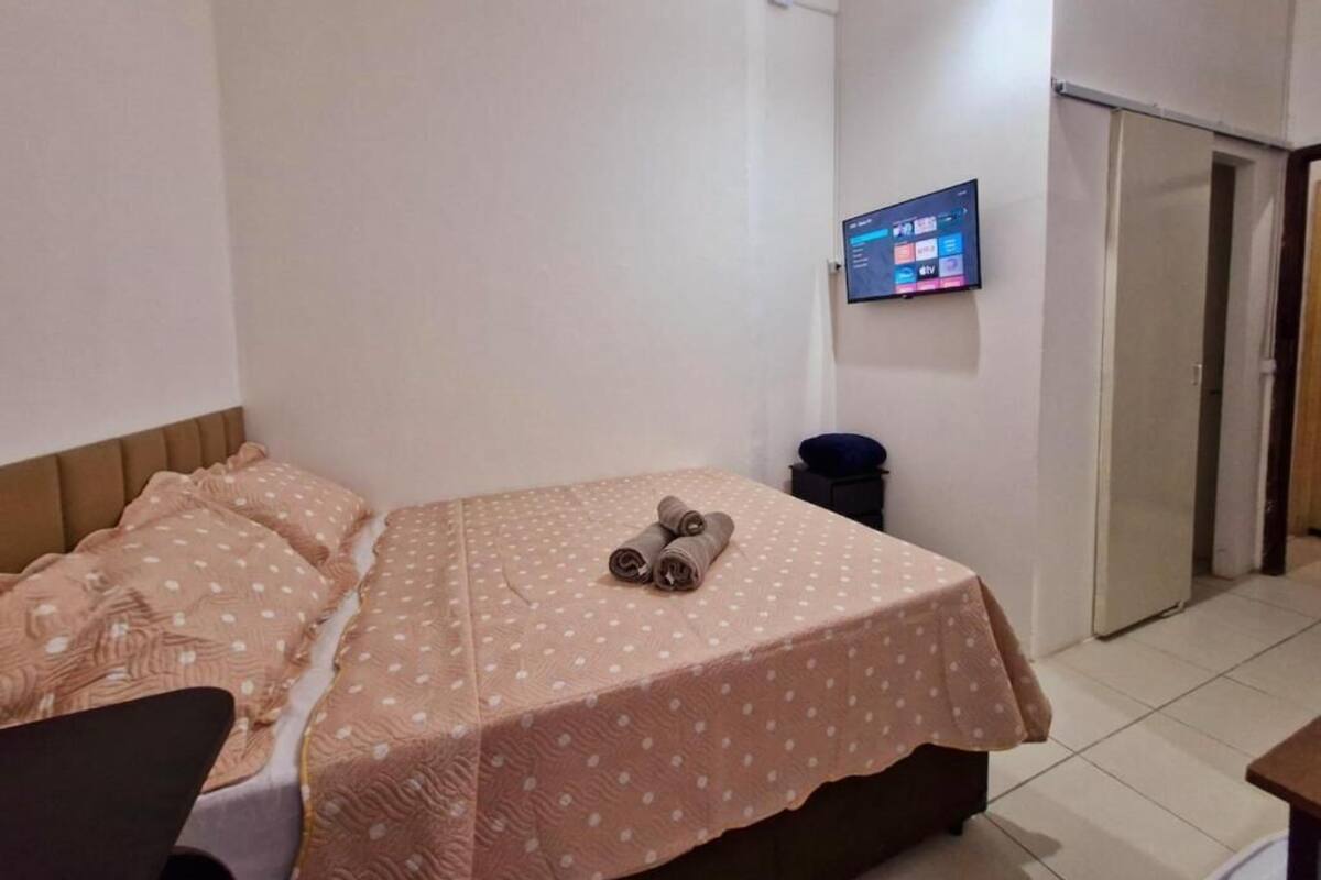 Habitación de hotel con cama, escritorio, televisor montado en la pared y puerta que da a otra habitación.