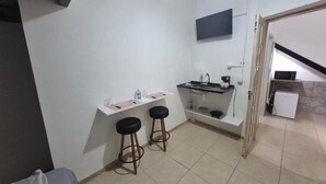 A compact kitchen area with a countertop, two stools, a small sink, and a microwave. - 360 Casa Praia Botafogo By SUHCasa (Rio de Janeiro)