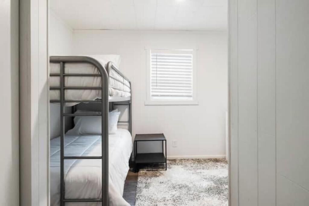 A bunk bed in a room with a small window and a nightstand.