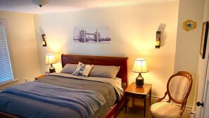A neatly made bed with a headboard, two bedside tables with lamps, a chair, and a wall-mounted picture of a bridge. - London Maisonette: Black Door
• Great space in a small town close to a big city! (London)