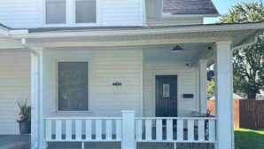 A two-story house with a front porch, a small front yard, and a wooden fence in the background. - London Maisonette: Black Door
• Great space in a small town close to a big city! (London)