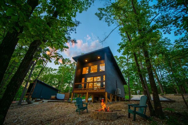 Une cabane moderne dotée d’une terrasse, entourée d’arbres.