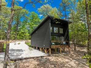 Una cabaña con terraza, rodeada de árboles.