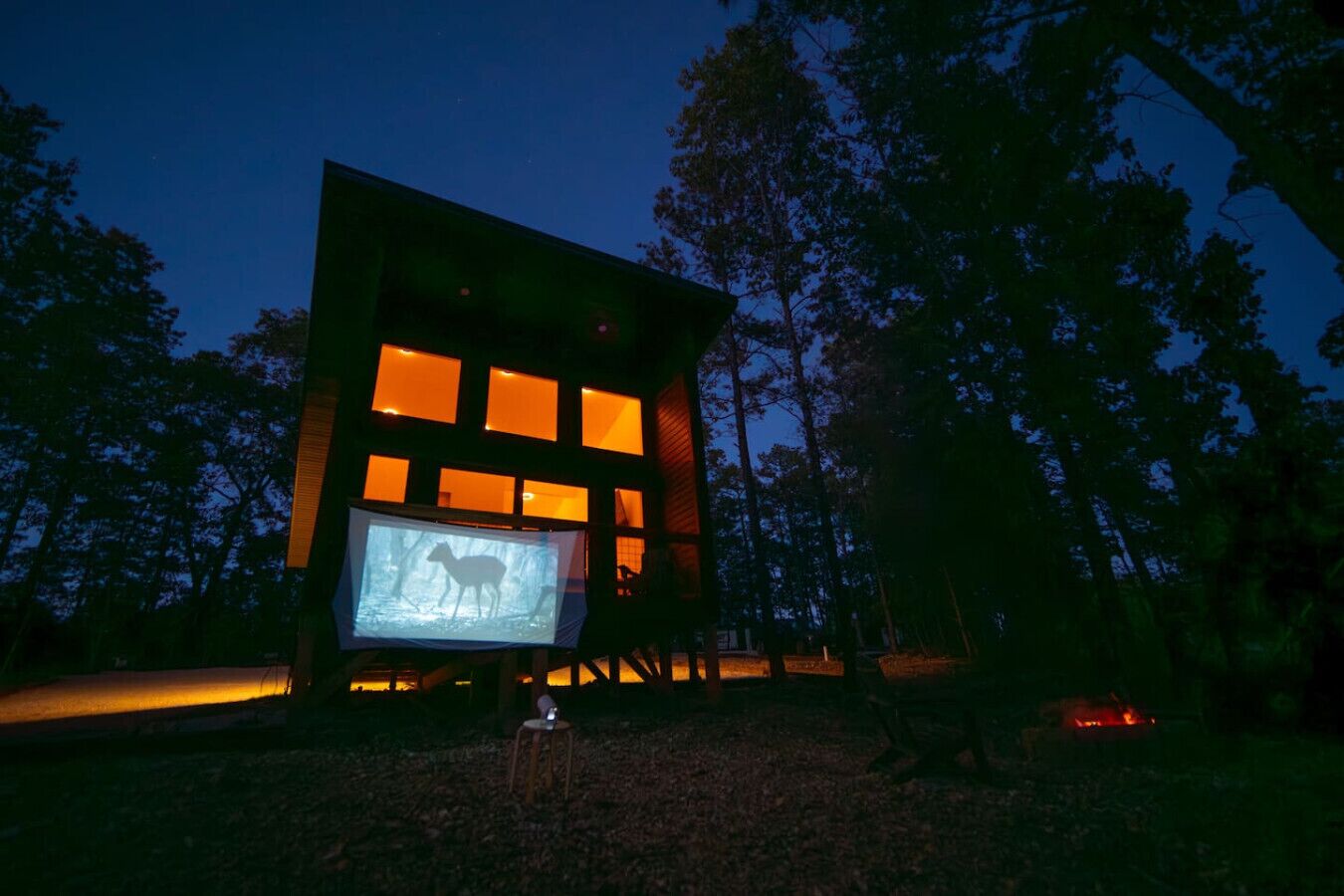 Un edificio moderno con ventanas iluminadas y una pantalla que muestra una imagen de un ciervo.