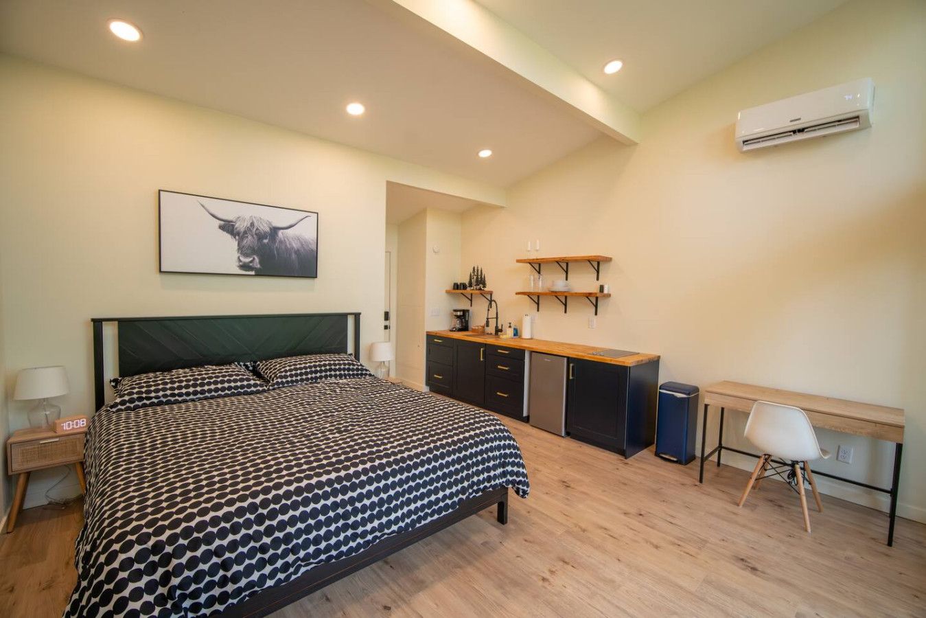 Una camera da letto con un letto, una scrivania, angolo cottura e condizionatore.