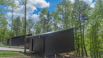 Two wooden cabins in a forest setting with a clear sky.