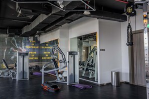 A gym with exercise equipment, a mirror, and a motivational poster on the wall.