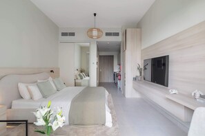 A modern bedroom with a large bed, a television mounted on the wall, and a hallway leading to a bathroom. - Brand New Sleek Luxury Studio (Dubai)