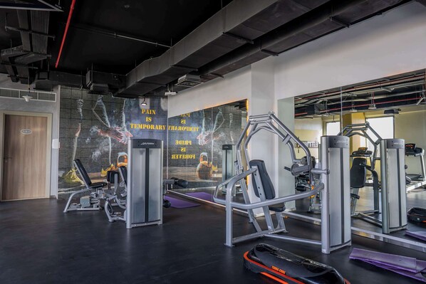 A gym with various exercise equipment, a large mirror, and a motivational quote on the wall.