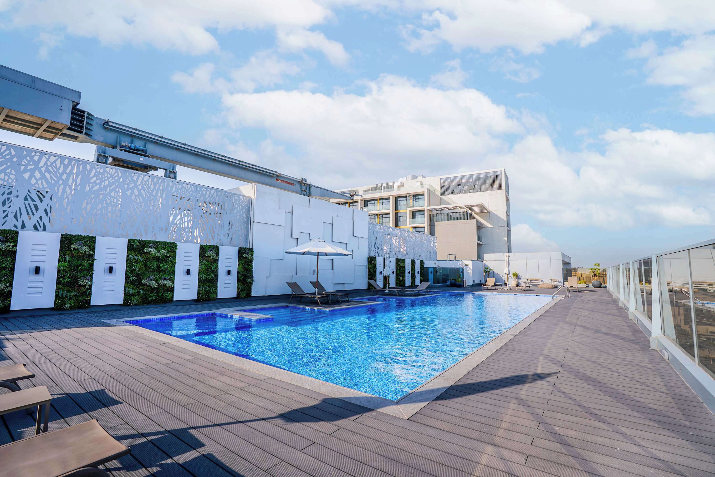 A rooftop swimming pool with lounge chairs and a modern building in the background.