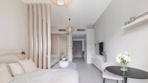 A modern hotel room with a large bed, a round dining table, and a sofa.