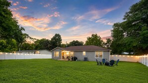 A single-story house with a covered patio area, a barbecue grill, and outdoor seating. - 4BR Home | Firepit + Yard | Near Historic Downtown (St. Augustine)