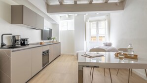 Una cocina moderna con horno empotrado, cafetera y televisor sobre la encimera.