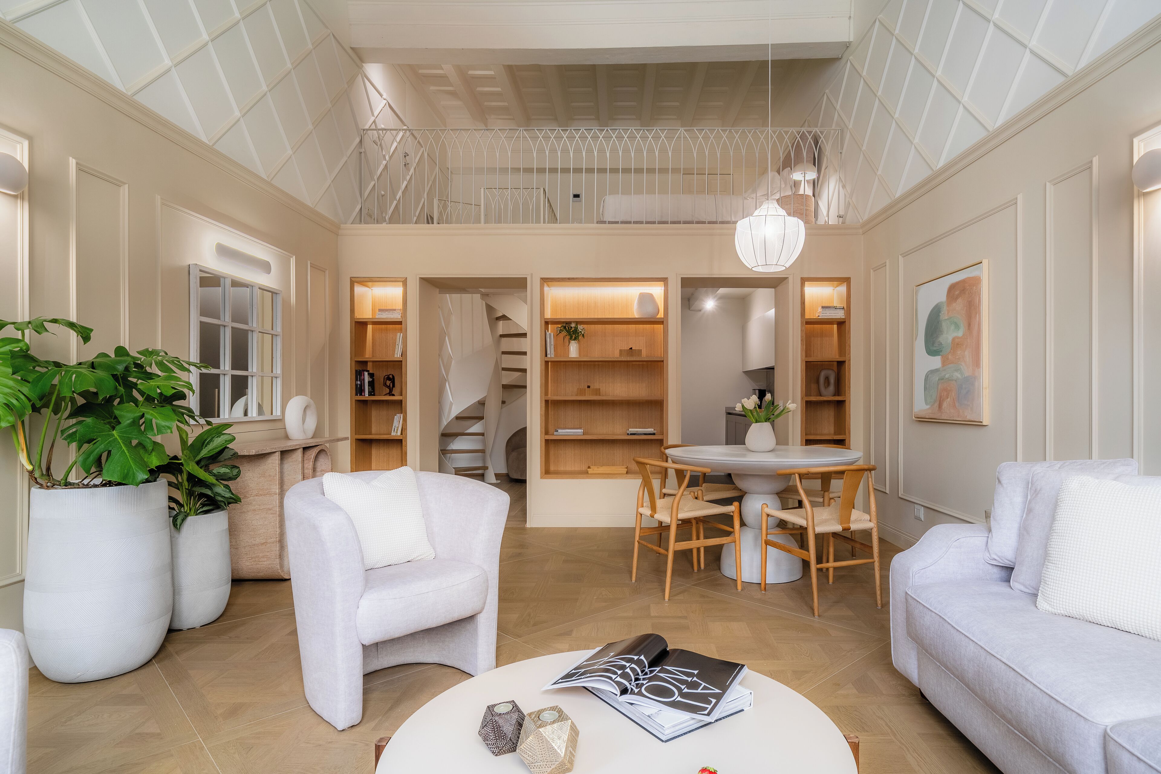 A spacious living room with a high ceiling, a staircase, and a dining area.