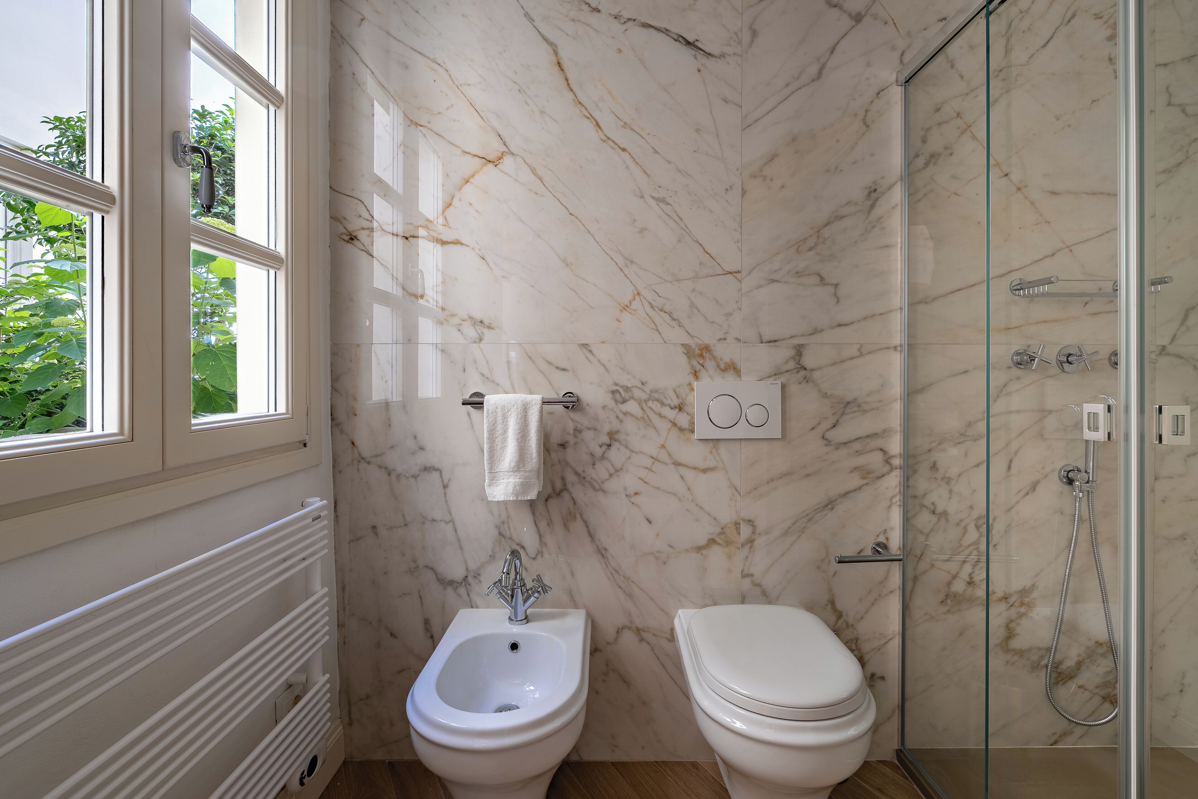 A bathroom with a bidet, toilet, and glass-enclosed shower.