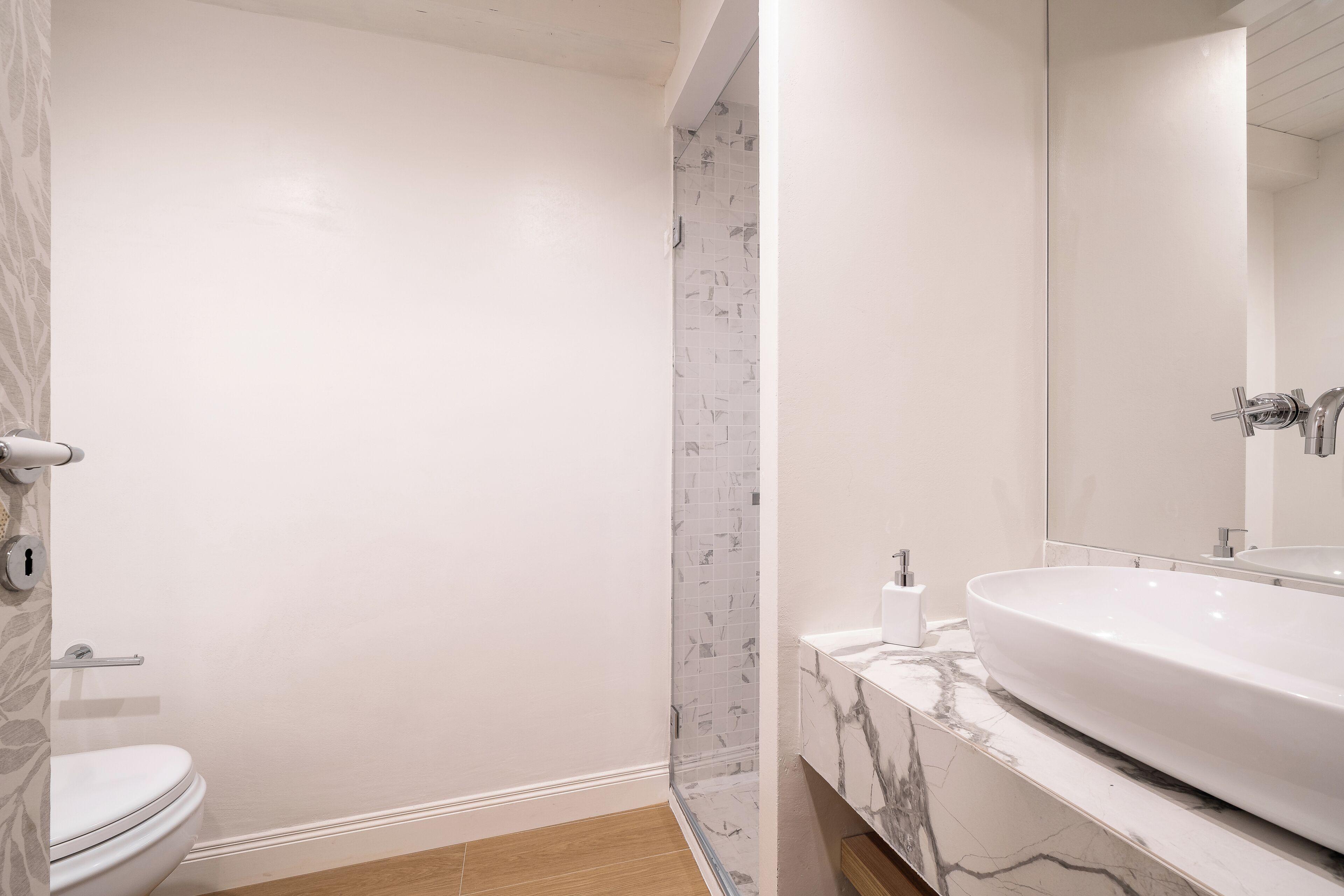 A bathroom with a white toilet, a shower with a glass door, and a sink with a marble countertop.