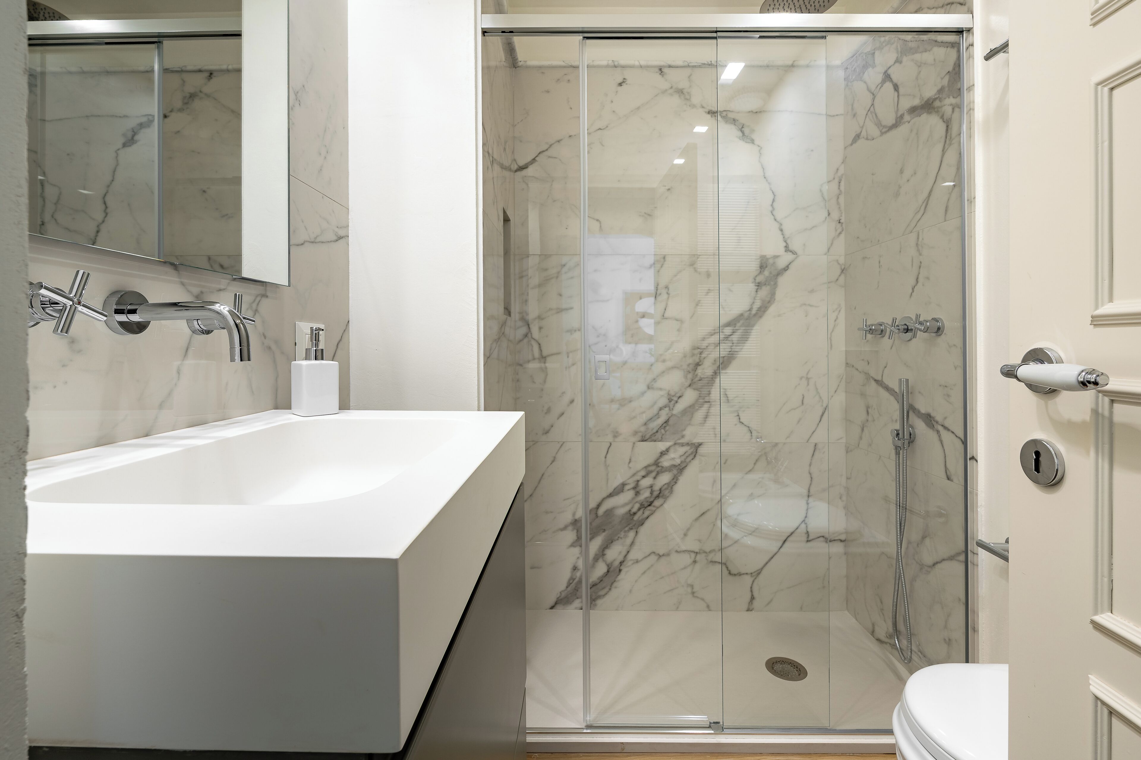 Un baño moderno con una bañera blanca grande, una ducha con mampara de vidrio y un inodoro.