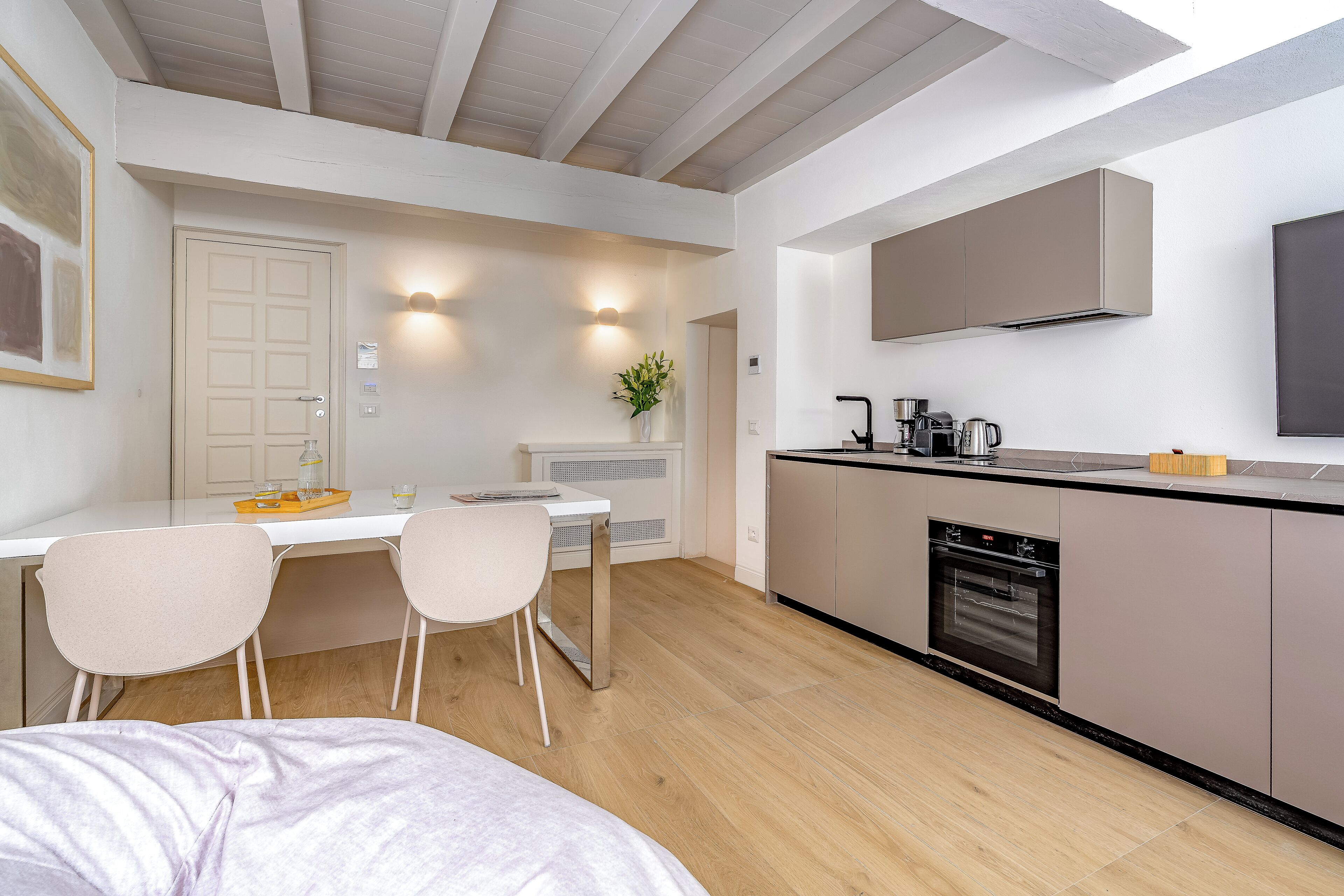A modern kitchen with a dining area, wooden flooring, and a built-in oven.