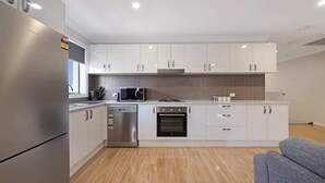 Una cocina moderna con armarios blancos, electrodomésticos de acero inoxidable y piso de madera.