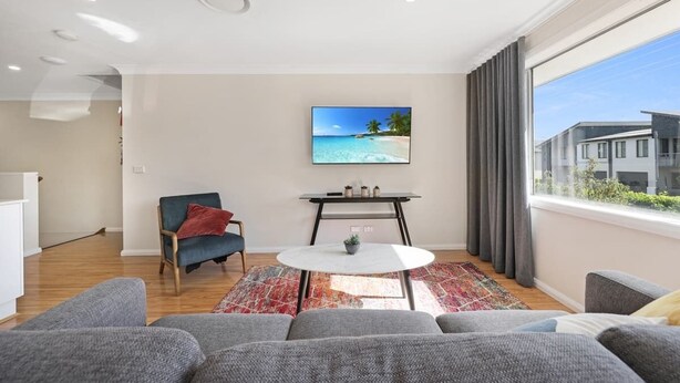 A modern living room with a flat-screen TV, a round coffee table, and a sofa.