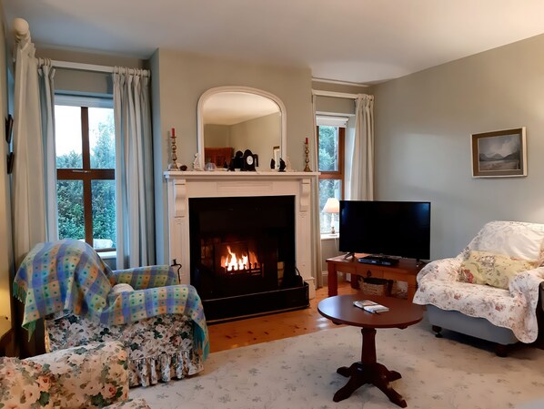A living room with a fireplace, a television, and two chairs. - Moynish Mor Mulranny (Bunnahowna)