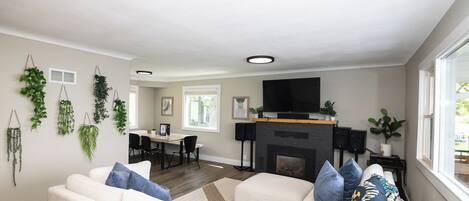 Ein modernes Wohnzimmer mit einem weißen Sofa, blauen Kissen, einem Kamin und hängenden Pflanzen.