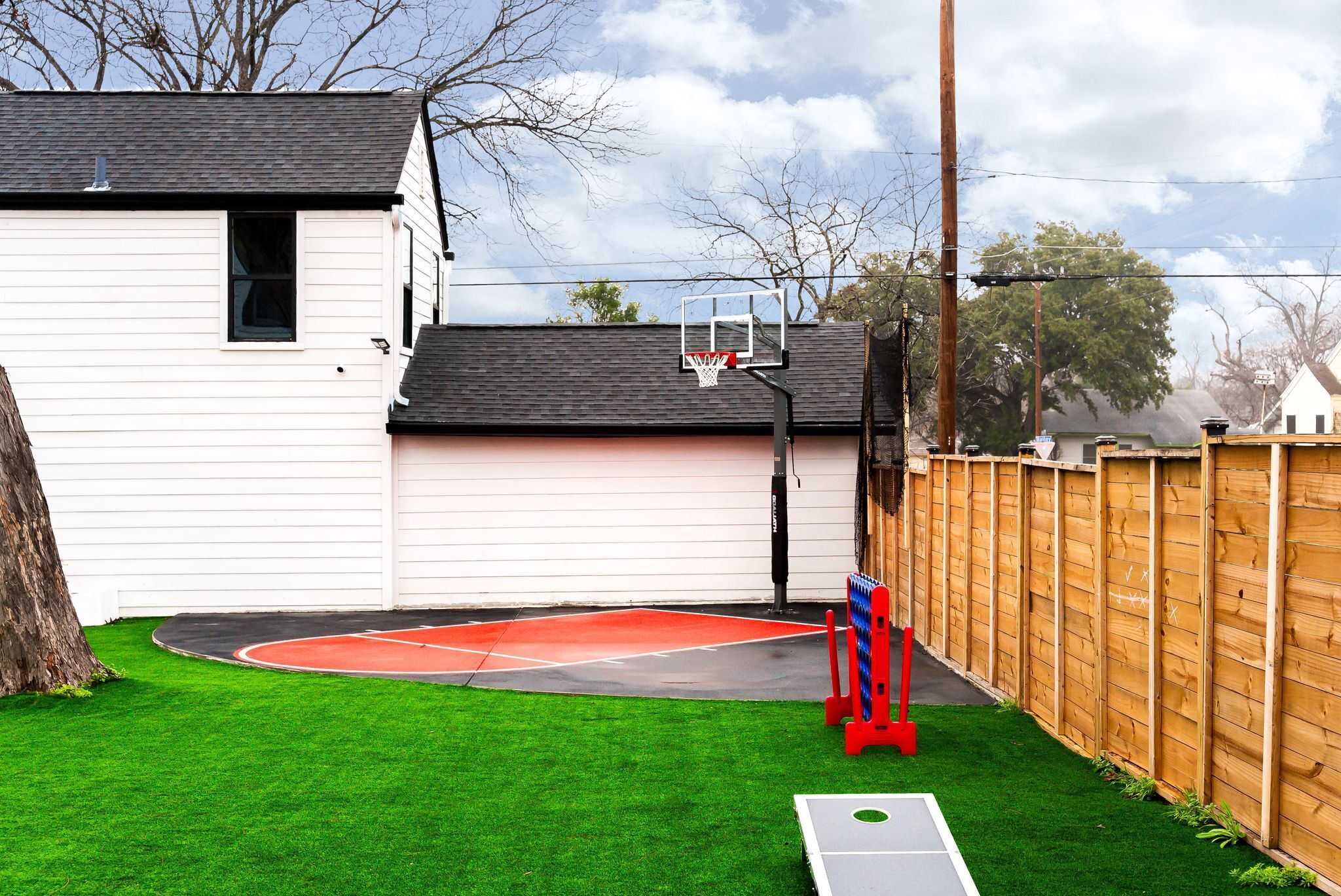 A basketball court with a hoop, a red shovel, and a wooden fence.