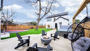 An outdoor patio with Adirondack chairs, a fire pit, and a hanging chair. - The Perfect Getaway! Insta:Thewhitehouse._ (San Antonio)