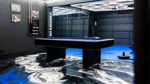 A pool table in a room with a blue floor, hexagonal ceiling lights, and a wall with billiards equipment. - The Perfect Getaway! Insta:Thewhitehouse._ (San Antonio)