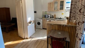 A compact kitchen with wooden cabinets, a microwave, and a washing machine.