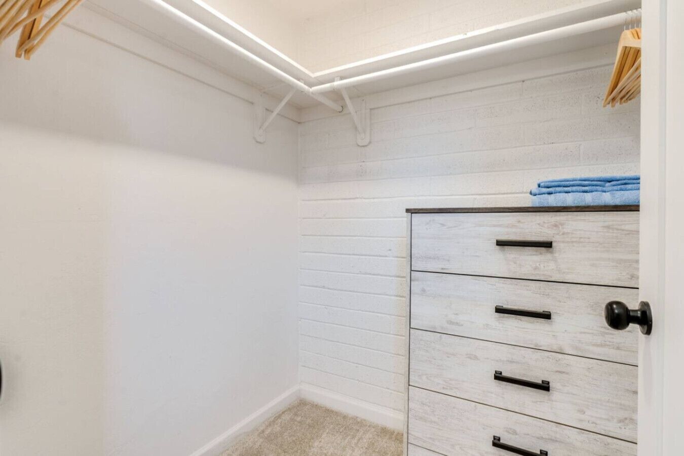Habitación de esquina con pared blanca, un mueble de madera con cajones y una lámpara en el techo.