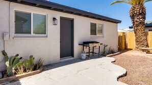 Une maison de plain-pied avec un patio, un barbecue et des cactus.