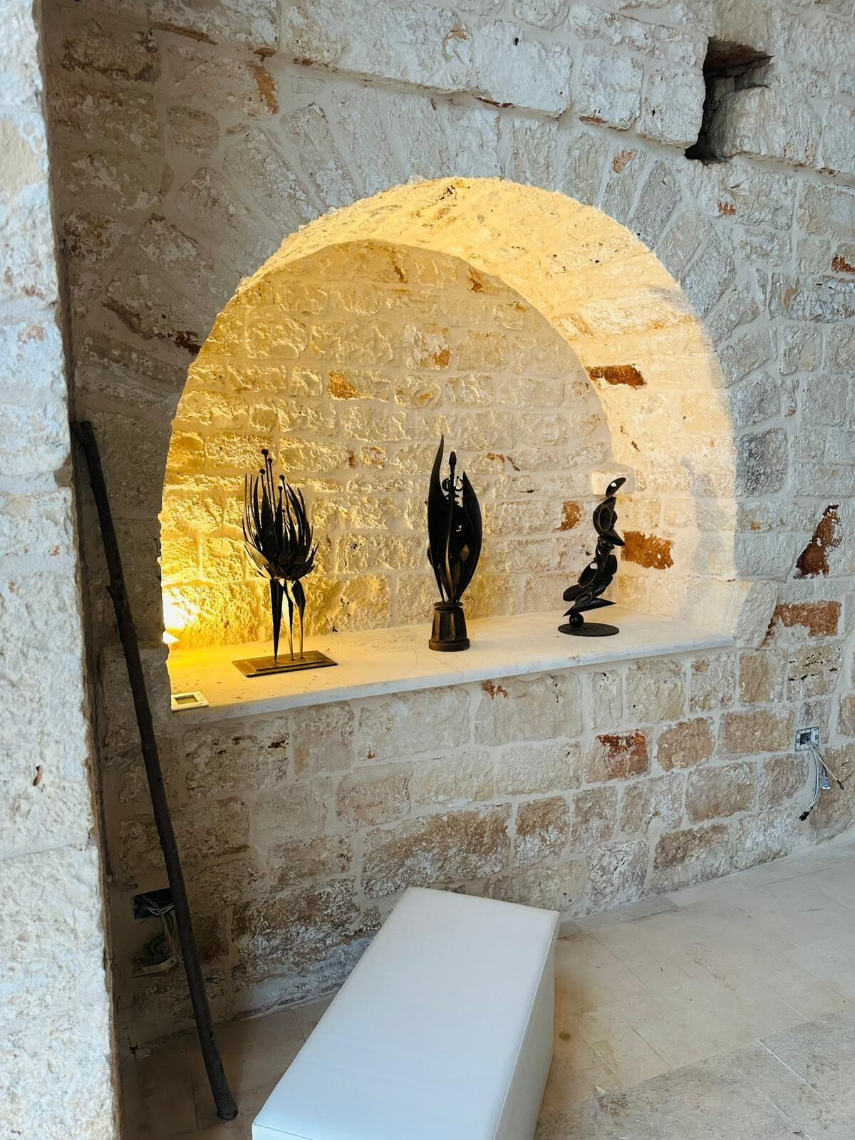 Una pared de piedra con un estante que muestra tres esculturas.