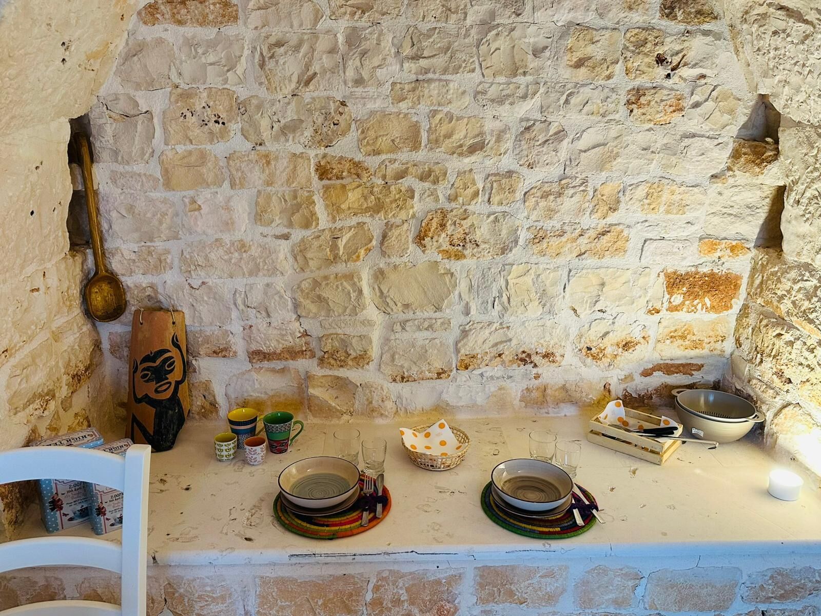 Pared de piedra con un montaje rústico para comer, que incluye platos, cuencos y una cuchara de madera.